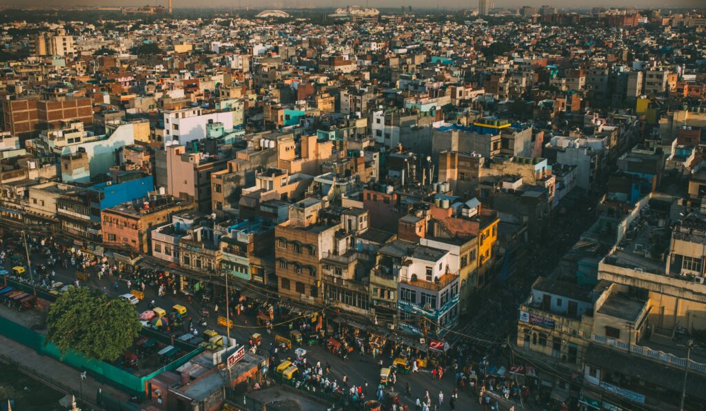 A vibrant aerial cityscape of Delhi, showcasing the bustling streets and diverse architecture under warm daylight.